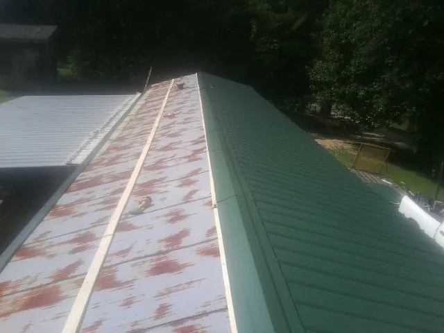 Old rusted panels beside newly installed green metal roofing — Wind Damage Roof Repair by Roofing Brothers in Bismarck