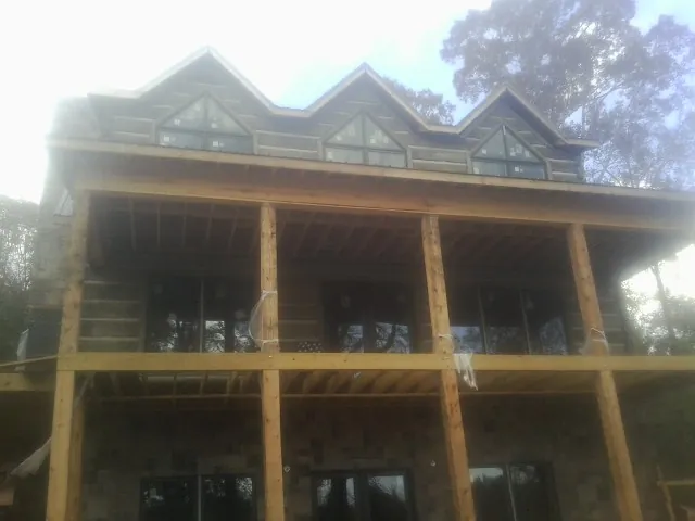 Dormers and porch framing on a large log home under construction — Roof Coating work by our crew in Bismarck