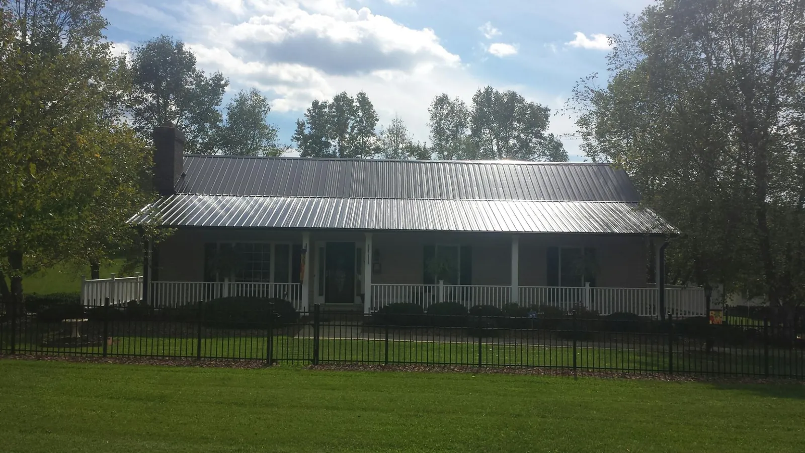 Gray metal roof on a brick ranch with a full width front porch — Gutter Guard Installation work by our crew in Bismarck