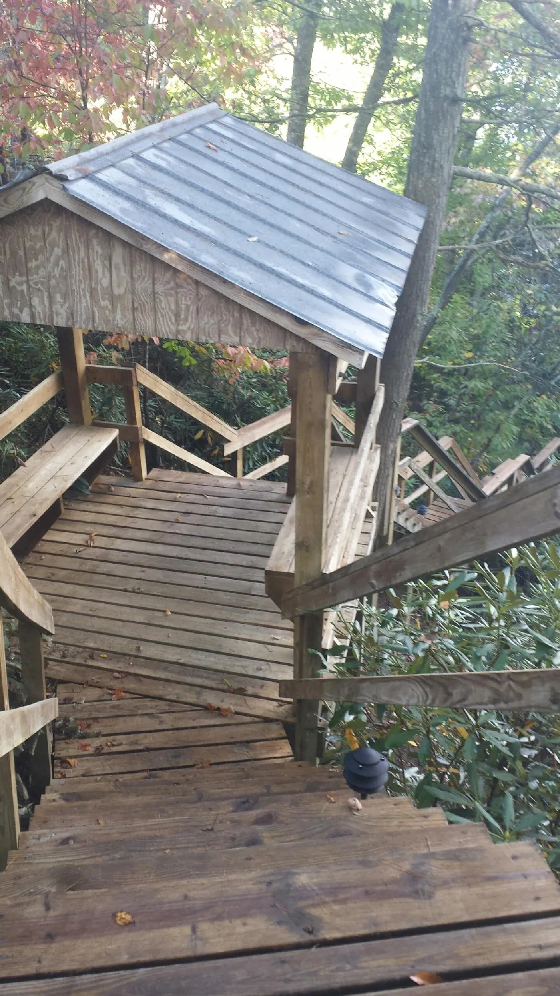 Metal roofed shelter over wooden steps on a wooded walkway — Skylight Repair & Installation work by our crew in Bismarck